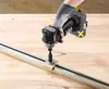A person wearing a glove is using a cordless impact driver to attach a clamp to a metal rail on a wooden surface. Produktbild-Vorschau