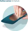 A hand is inserting a clear gel insole into a teal high-heeled shoe. Produktbild-Vorschau
