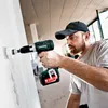 A man is using a cordless drill to make a hole in a wall. Produktbild-Vorschau
