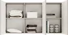 A close-up view of an open, modern, gray sideboard with multiple shelves and compartments, neatly organized with folded linens, books, and decorative items. Produktbild-Vorschau