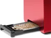 A close-up view of a red toaster with its crumb tray extended and filled with crumbs. Voir les images du produit