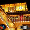 Christmas lights are hung on the roof of a house, with a red bow and garland also visible. Náhled obrázku produktu