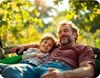 A father and son are relaxing on a swing in a sunny outdoor setting. Podgląd zdjęcia produktu