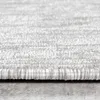 A close-up view of the edge of a cream-colored rug with a textured surface. Produktbild-Vorschau