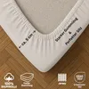 A close-up of a beige fitted sheet corner on a wooden floor, highlighting features with text and icons. Produktbild-Vorschau