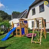 A wooden playground set with a slide, swings, and climbing net is set up in a grassy backyard next to a modern house. Podgląd zdjęcia produktu