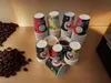 A collection of disposable coffee cups stacked on a wooden surface, with coffee beans scattered to the left. Produktbild-Vorschau