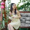 A young woman is sitting on a garden swing, reading a book. Náhled obrázku produktu