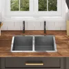 A kitchen sink area with a double basin sink, wooden countertop, and white subway tile backsplash. Voir les images du produit