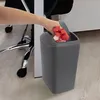 A hand is placing a red cloth into a dark gray trash can next to an office chair. Produktbild-Vorschau