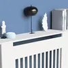 A white radiator cover with decorative items on top, set against a blue wall. Anteprima dell’immagine prodotto