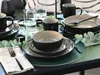 A table setting with dinnerware and cutlery, decorated with eucalyptus leaves. Produktbild-Vorschau