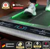 A close-up shot of a person's feet on a treadmill with a digital display showing speed and time. The treadmill has green LED lighting. Produktbild-Vorschau