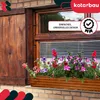 A wooden planter box filled with colorful flowers sits on a brick windowsill below a wooden window frame and shutters. Náhľad obrázku produktu