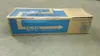 A cardboard box for a Kyocera toner kit sits on a concrete floor. Voir les images du produit