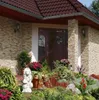 A house entrance with stone facade and a garden in front. Podgląd zdjęcia produktu