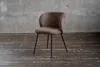 A single chair is shown in a room with a concrete wall and wooden floor. Produktbild-Vorschau