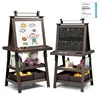 Two children's easels are displayed side-by-side against a white background. The easel on the left has a drawing on its whiteboard, while the one on the right has drawings on its chalkboard. Both easels have storage shelves below. Podgląd zdjęcia produktu
