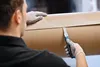 A person wearing gloves is cutting a large roll of brown paper with a utility knife. Voir les images du produit