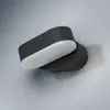 A modern, dark gray outdoor wall light with a white diffuser, mounted on a textured light gray wall. Produktbild-Vorschau