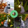 A collage of four images showing a solar-powered elephant garden statue with a lantern in different outdoor settings. Produktbild-Vorschau