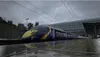 A train with a rainbow stripe on a rainy day with lightning in the background. Náhled obrázku produktu