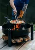 A person is cooking food in a large metal fire pit outdoors. Náhled obrázku produktu