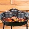 Three small cast iron pots with lids are placed on a grill rack over hot coals. Voir les images du produit