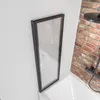 A shower wall is installed next to a bathtub, with a brick wall in the background. Produktbild-Vorschau
