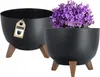 Two black planters on wooden legs, one with purple flowers. Náhled obrázku produktu