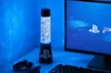 A PlayStation-themed lava lamp sits on a desk next to a computer monitor displaying the PlayStation logo. Podgląd zdjęcia produktu
