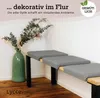 A corner of a room with a bench and a vase of flowers. Produktbild-Vorschau
