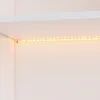 A close-up view of an LED light strip installed under a white shelf. Produktbild-Vorschau