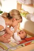 A mother is playing with her baby on a changing table. Produktbild-Vorschau