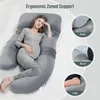 A pregnant woman is lying on a large U-shaped pillow on a bed, with close-up insets showing how the pillow supports her belly, back, and legs. Podgląd zdjęcia produktu
