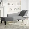 A grey chaise lounge is placed on a patterned rug in a living room setting, with a fireplace and bookshelves visible in the background. Produktbild-Vorschau
