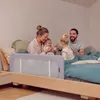 A family is sitting on a bed with a baby bed rail. Anteprima dell’immagine prodotto