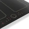 A close-up view of a black induction cooktop with illuminated digital controls and markings. Produktbild-Vorschau