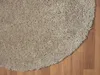 A close-up view of a round, beige shaggy rug on a wooden floor. Náhľad obrázku produktu