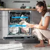 A woman is loading dishes into an open dishwasher in a modern kitchen. Anteprima dell’immagine prodotto