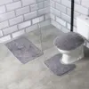 A bathroom scene with a toilet and three fluffy gray bath mats. Náhled obrázku produktu