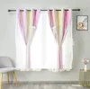 A pair of ombre curtains in pink and yellow with sheer voile overlays, decorated with small white stars and bows, hanging in a window. A grey chair is visible to the left, and a small gold side table with a vase of flowers is on the right. Náhled obrázku produktu