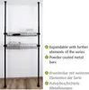 A black metal shelving unit with two wire baskets, set against a white wall and wooden floor. Náhled obrázku produktu