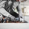 A person is using an angle grinder to cut metal, with sparks flying. Produktbild-Vorschau