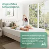 A couple is relaxing on a mattress in a bright bedroom with large windows overlooking a garden. Produktbild-Vorschau