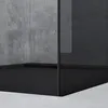A close-up view of a modern shower enclosure with concrete-like walls and a black base. Produktbild-Vorschau