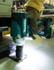 A hand wearing a glove is using a cordless impact wrench to tighten a bolt on a metal surface. Produktbild-Vorschau