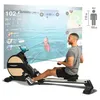 A man is using a rowing machine with a large screen displaying a virtual rowing environment and performance metrics. Produktbild-Vorschau