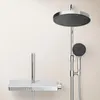 A modern chrome shower system with a large overhead rain shower and a handheld showerhead, mounted against a light-colored wall. Produktbild-Vorschau