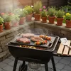 A barbecue grill with steaks, sausages, and skewers cooking on it, surrounded by potted plants. Náhľad obrázku produktu